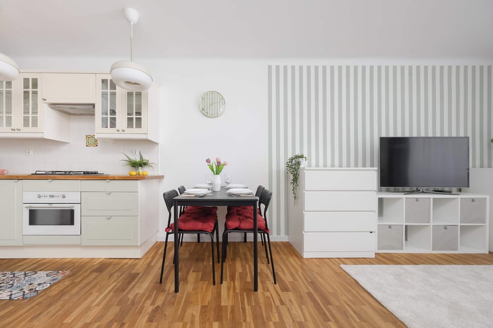 A close-up shot of a kitchen countertop featuring a kettle, cups, and a decorative vase. The clean white surface highlights the tidy and organized arrangement.