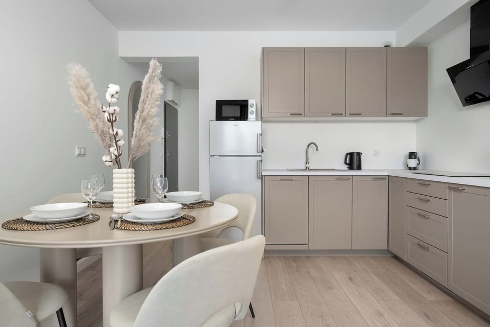 A sleek modern kitchen with light-colored cabinetry, integrated appliances, and a clean countertop complemented by subtle decorative touches.