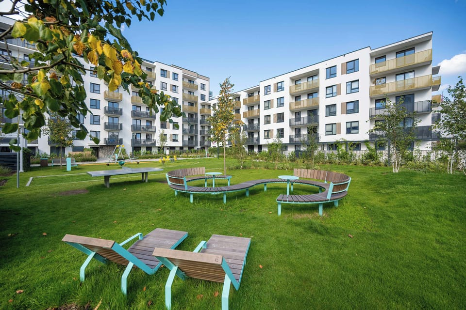 Another view of the landscaped communal garden featuring lawns, trees, and outdoor amenities.