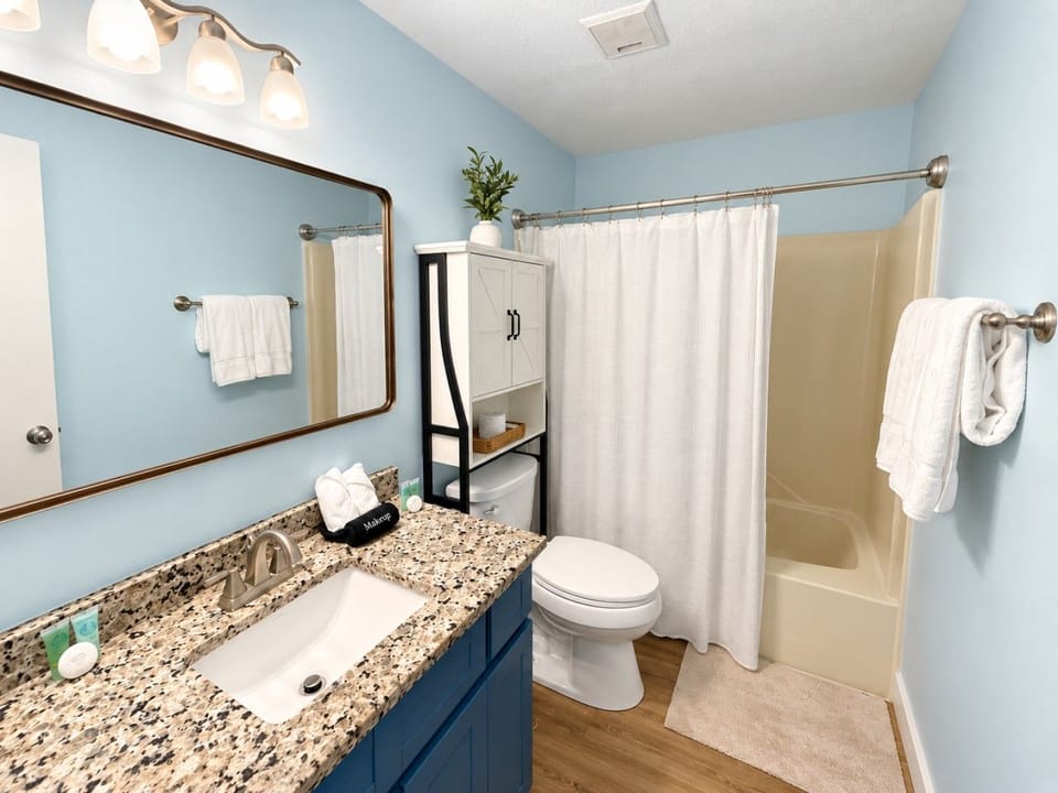 Clean bathroom with tub-shower and blue vanity