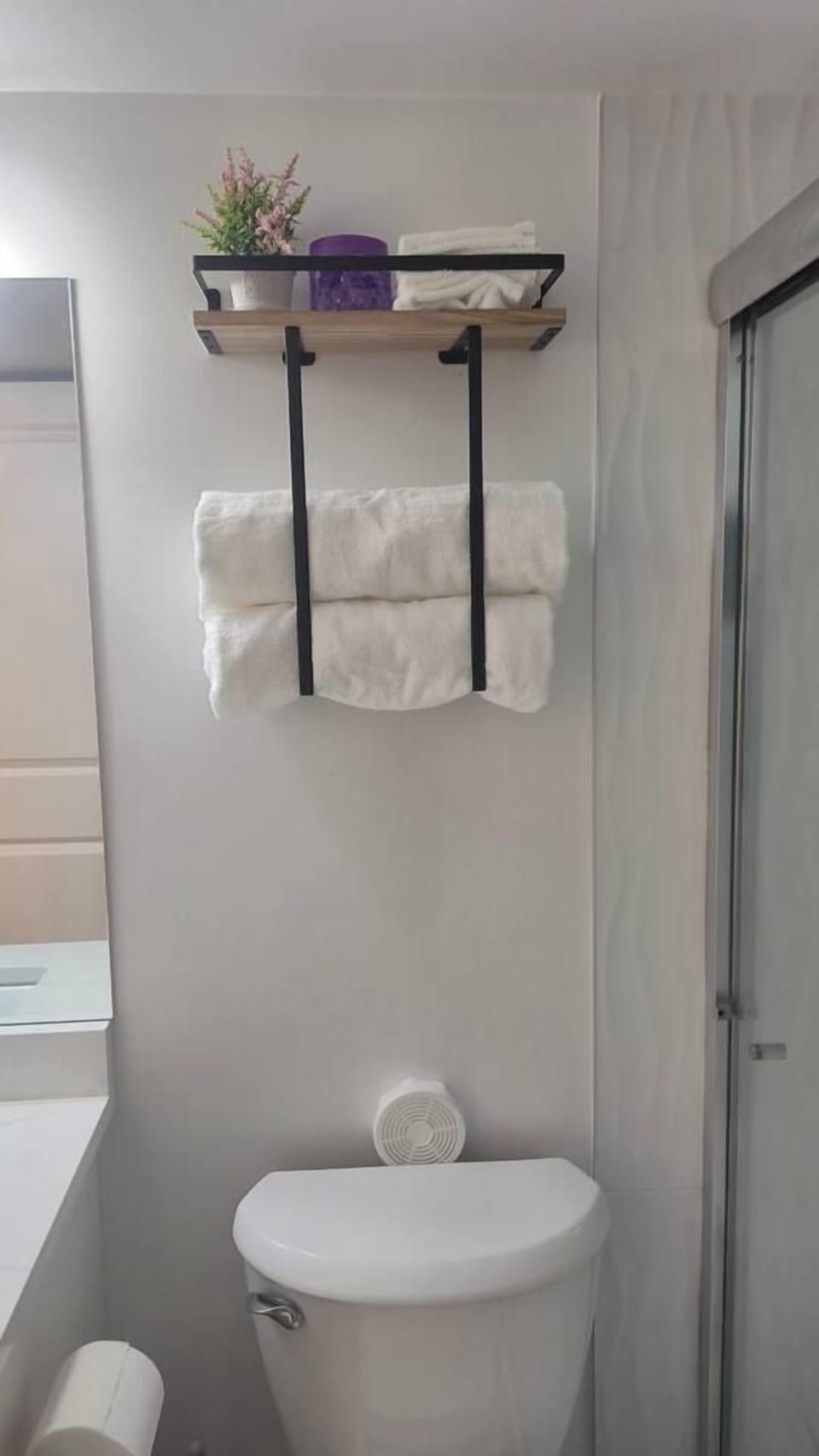 Bright modern bathroom with stylish shelving and fresh guest towels