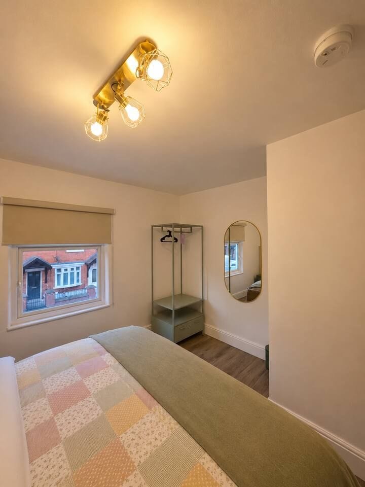 Bright, cozy bedroom with warm lighting, open wardrobe, and mirror