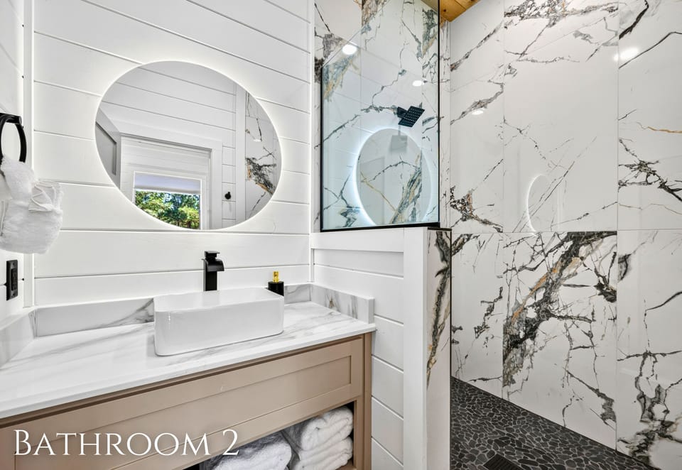 A bright vanity and striking marble-style shower surround bring a polished feel to the bathroom while providing plenty of space for getting ready.