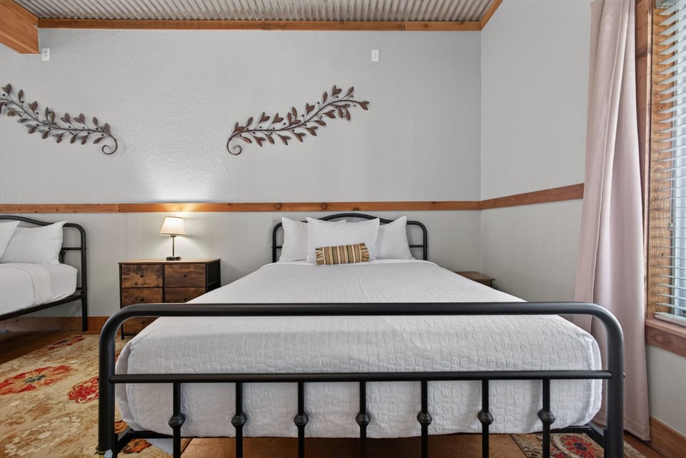 A bedroom furnished with black metal frame beds and rustic wood trim accents.