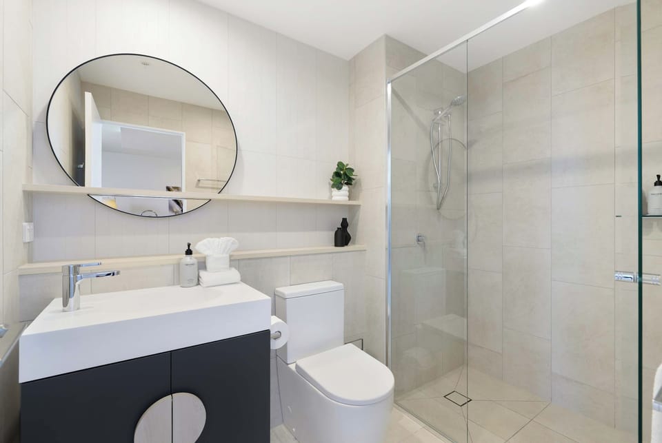 Modern Walk-In Bathroom
Refresh in this sleek, bright bathroom featuring a spacious glass walk-in shower and modern circular mirror. Generous vanity storage ensures total convenience.