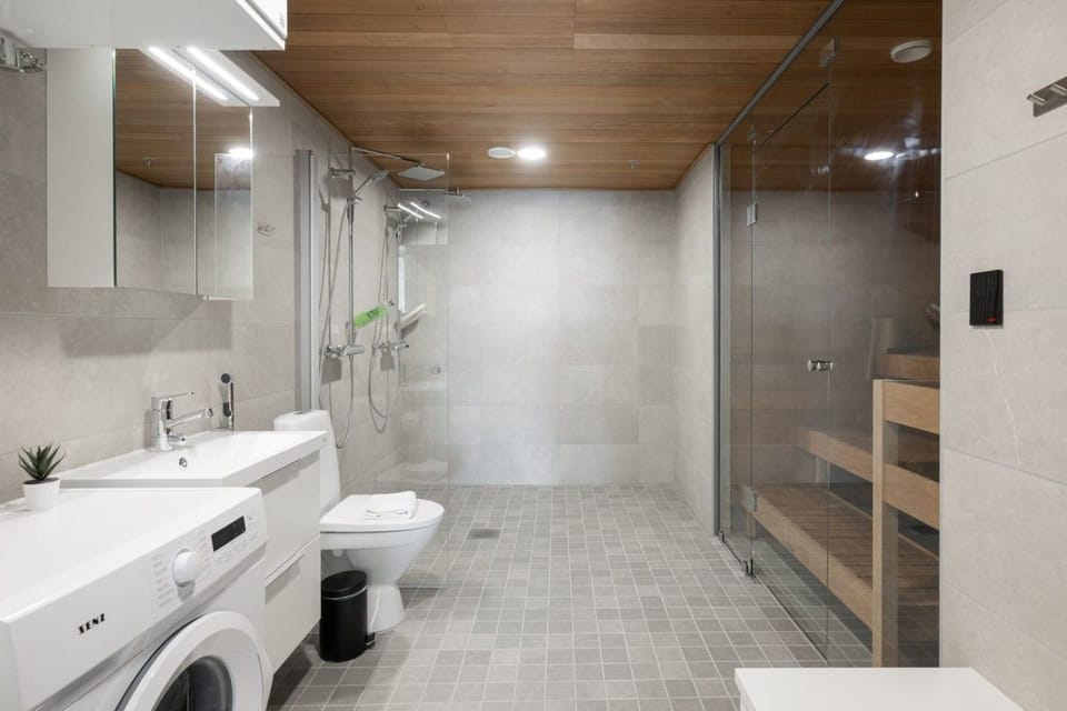 Modern bathroom with spacious walk-in shower, double vanity, and integrated laundry facilities.