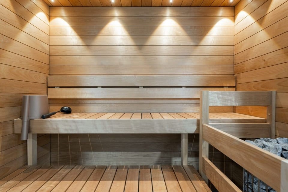 A beautifully finished sauna with tiered wooden benches and ambient lighting for a relaxing heat experience.