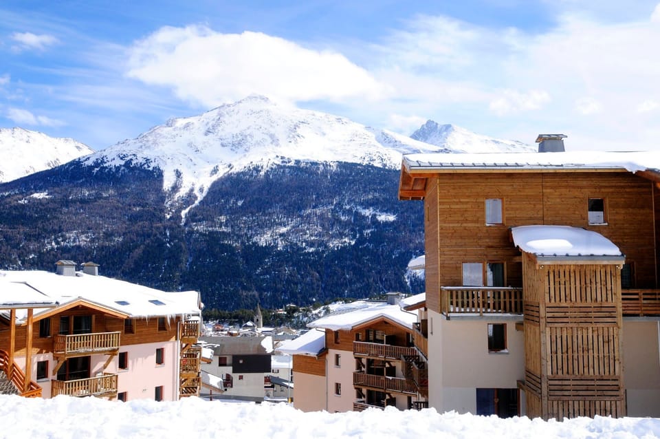 Timber-balconied buildings with a broad mountain panorama behind