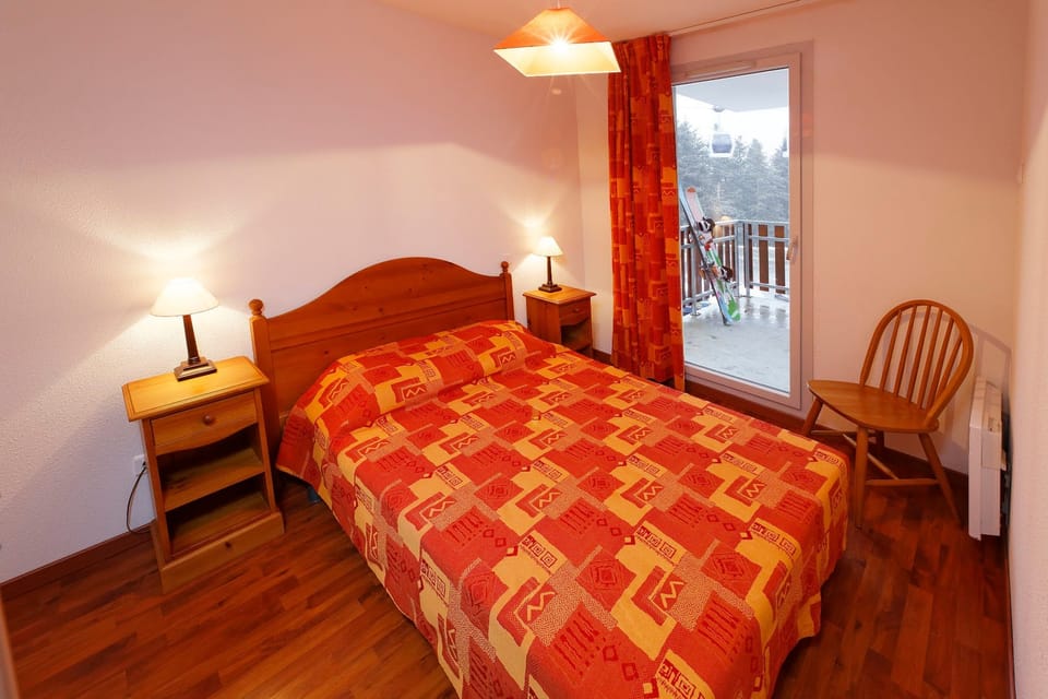 Cozy bedroom with balcony access, perfect for post-ski relaxation.
