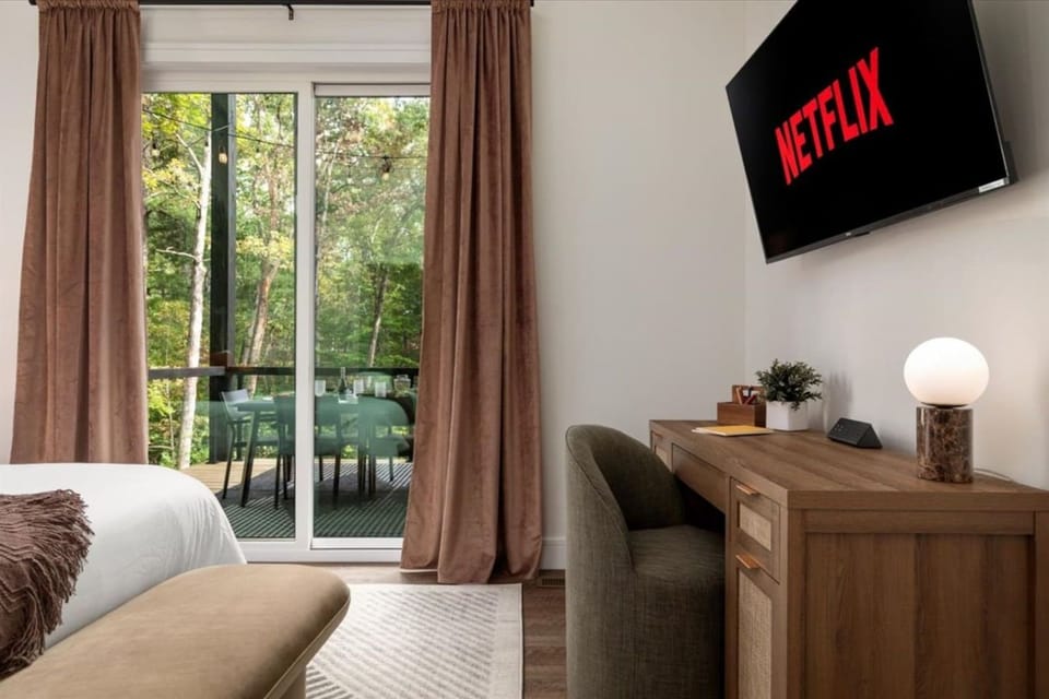 Bedroom workspace, Smart TV, and sliding doors opening onto the deck.