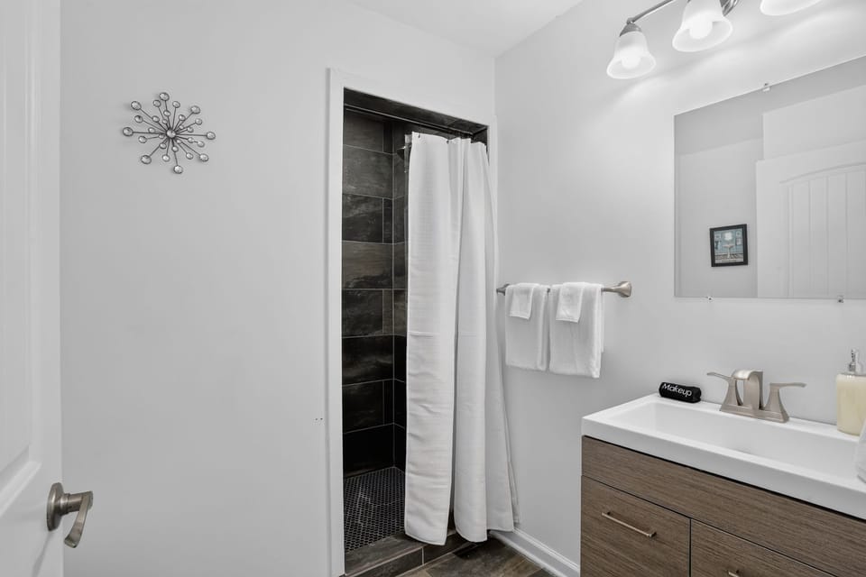 Modern bathroom with a spacious vanity, bright lighting, fresh towels, and a separate shower area for convenient group stays.