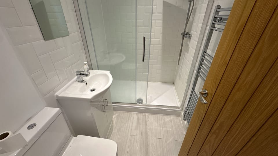 Bright modern bathroom with glass walk-in shower and heated towel rail