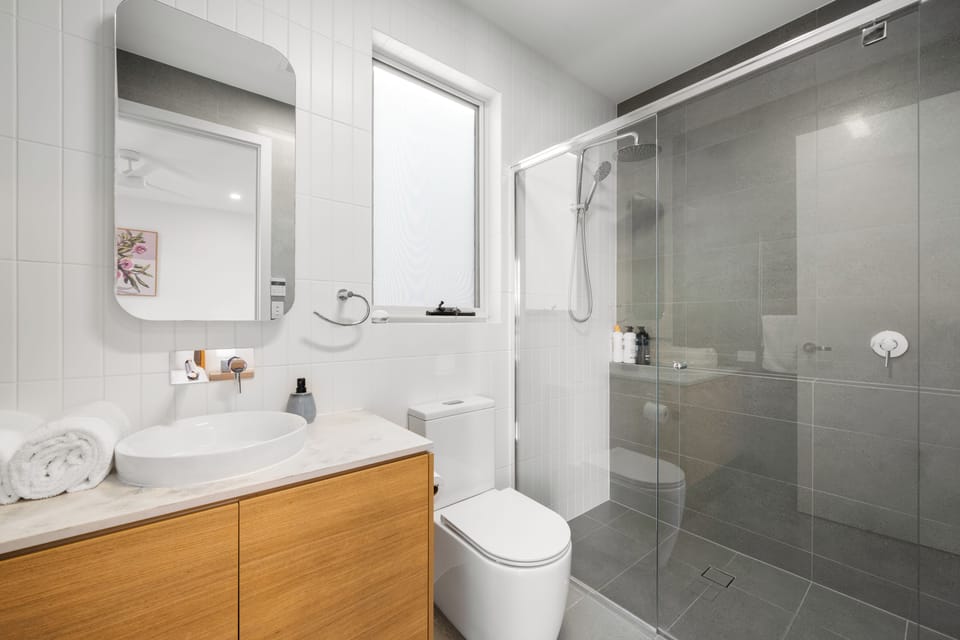 Refresh in the primary bedroom's private ensuite, complete with a spacious glass-enclosed shower and contemporary timber vanity.