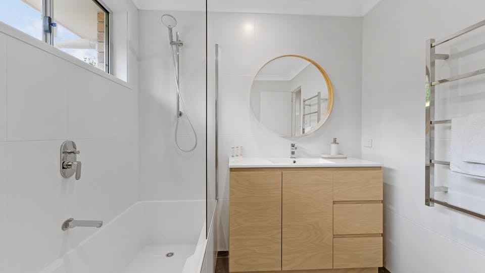 Clean bathroom interior highlighting a walk-in shower and round mirror.