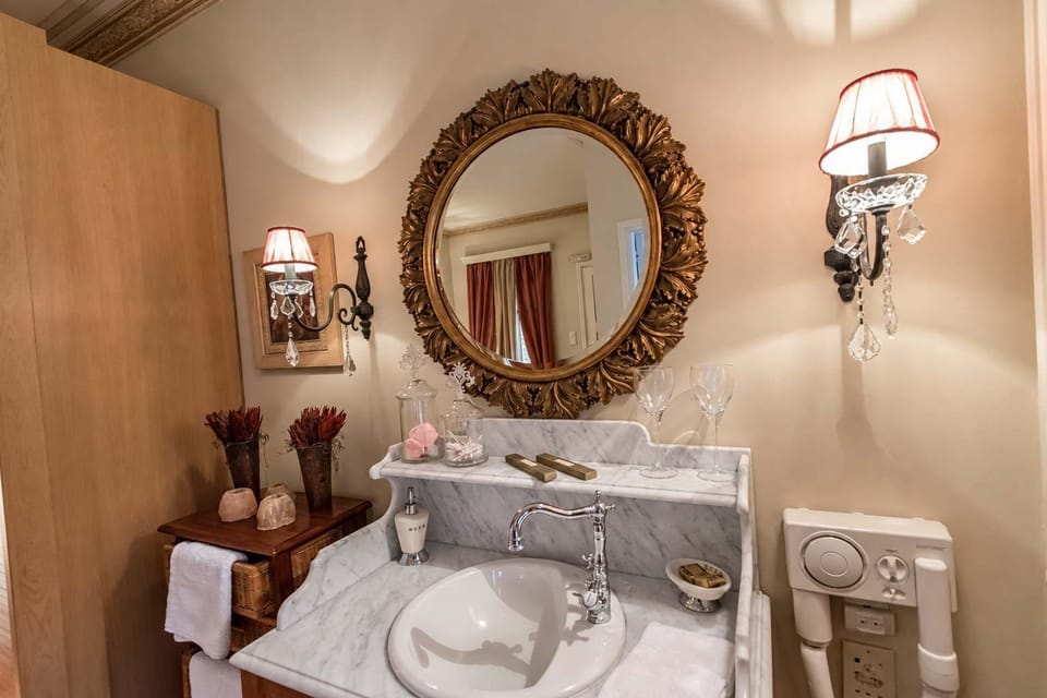 Elegant marble vanity with vintage-style fixtures and beautifully framed mirror.