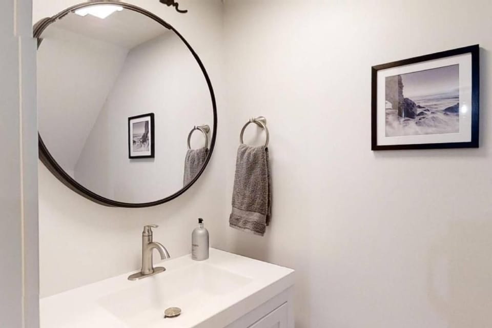Circular glass and brushed metal accents create a serene, modern nook for your morning routine. Soft, diffused light bounces off the clean vanity and minimalist art, offering a calm and organized start to your day.