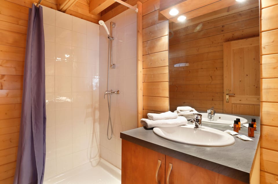 Crisp white tiles meet timber walls in the shower room.