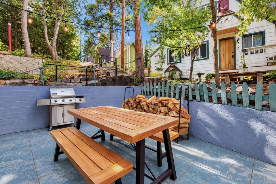 Gather outdoors for easy meals at the picnic table beside the grill and stacked firewood.