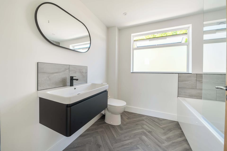First floor: modern bathroom vanity sink, complemented by a large round mirror.