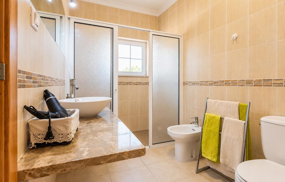 Modern bathroom with a bathtub and shower, vanity unit, toilet, and warm neutral tiled finishes.