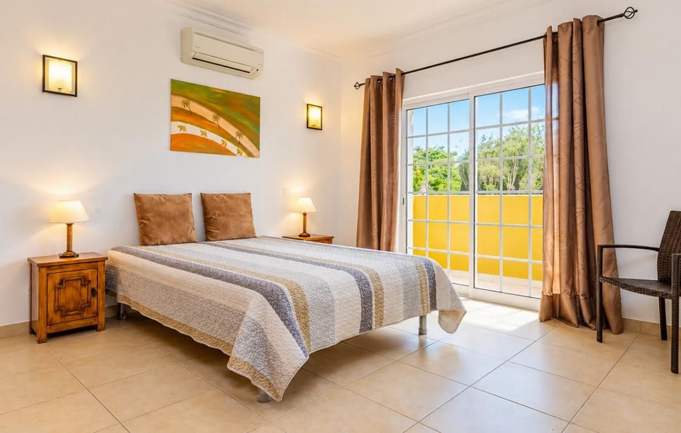Comfortable twin bedroom with air conditioning, bedside lighting, large windows, and direct access to the outdoor area.