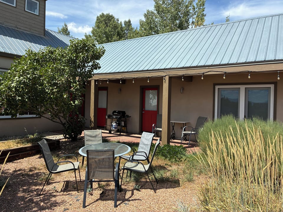Inviting outdoor retreat featuring a covered patio with string lights, comfortable seating, and a BBQ grill—perfect for your morning coffee or evening gatherings under the open sky.