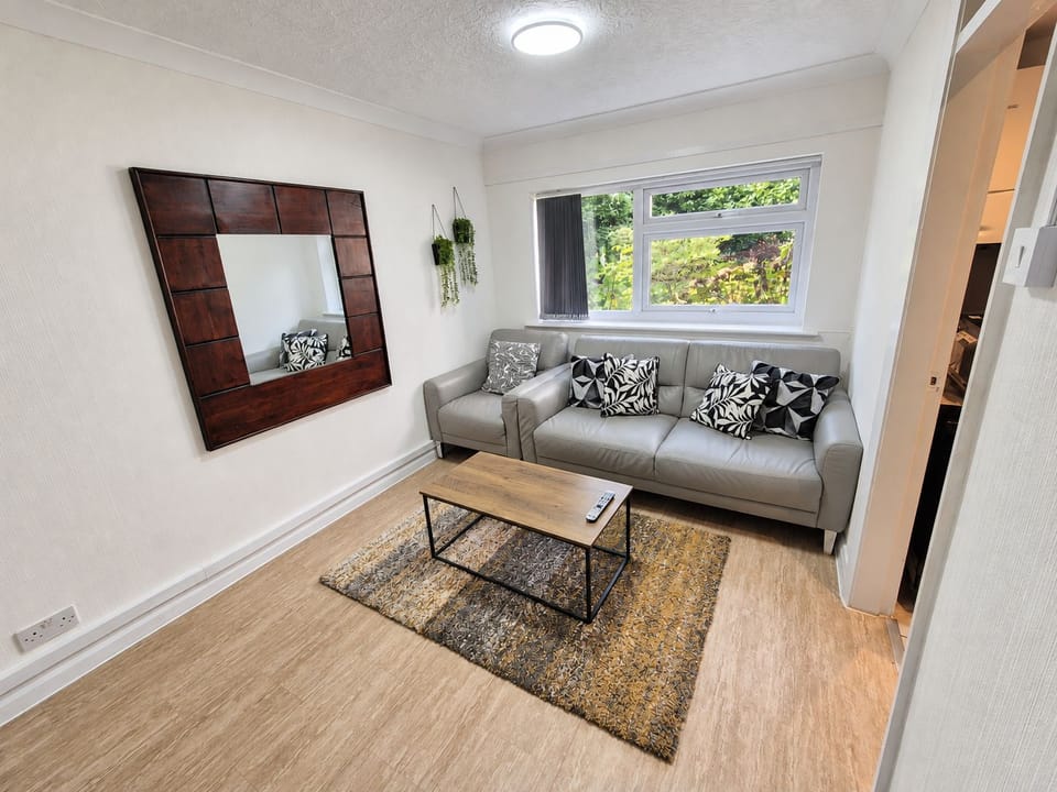 Living Room: Inviting open-plan area with a comfortable grey sofa, geometric patterned cushions, a natural wood coffee t
