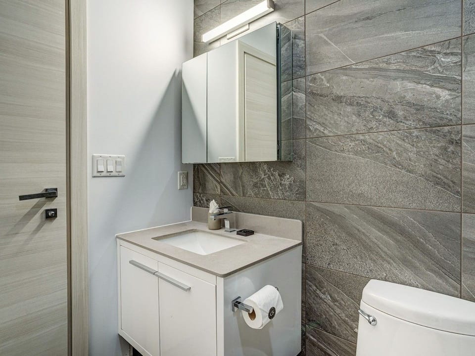 Modern bathroom with a sleek vanity, marble-style tilework, and clean contemporary finishes.