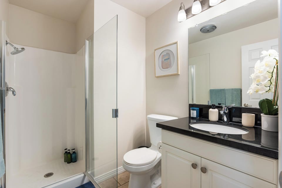 Bathroom with a glass shower, vanity, and toilet.