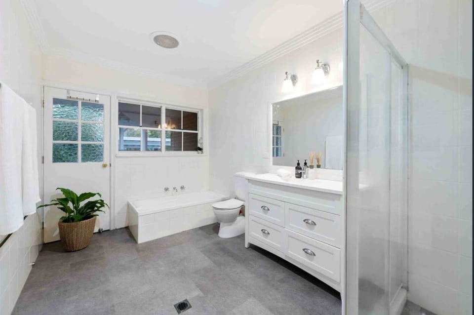 Contemporary bathroom interior showcasing a clean white vanity, walk-in shower, and a freestanding tub.   
