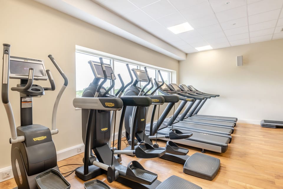 Bright on-site fitness room with treadmills and ellipticals