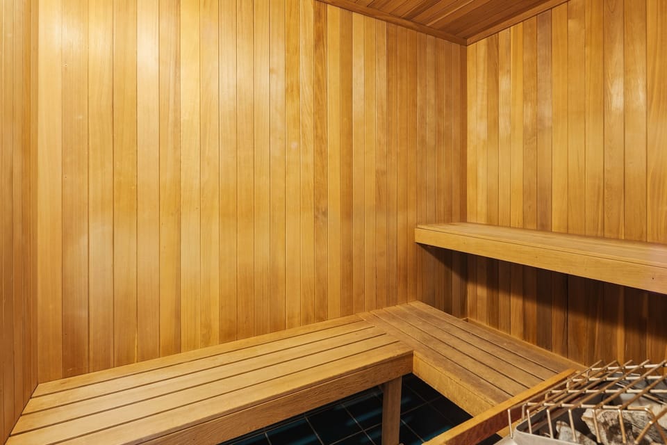 Indoor sauna with wooden paneled walls and tiered slatted benches.