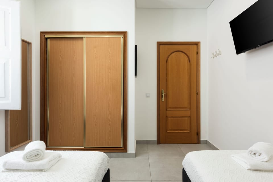 Bright twin room with wardrobe, wall TV, and crisp linens