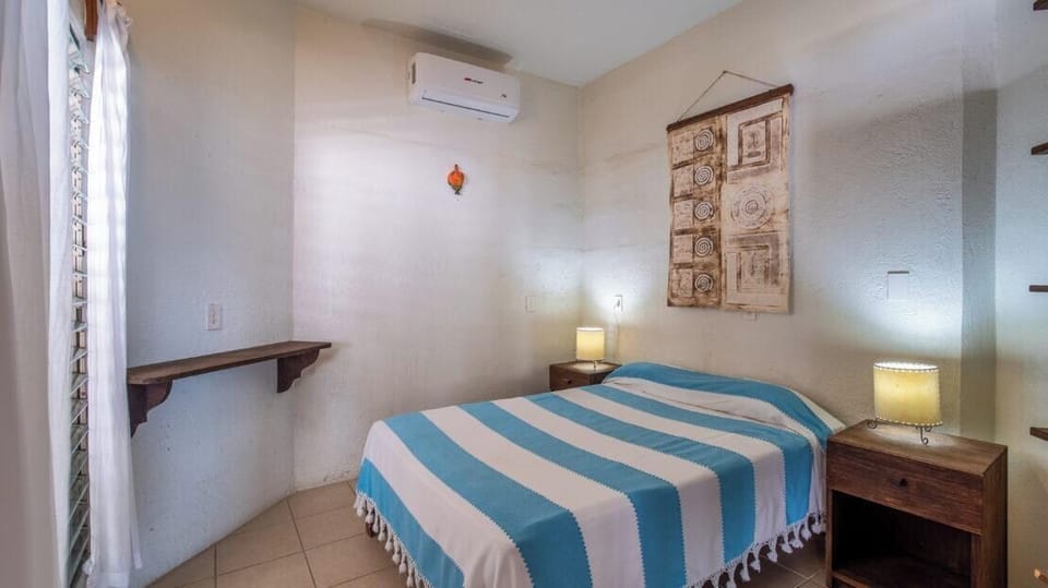 Bedroom with air conditioning, a wall shelf and bedside lamps.