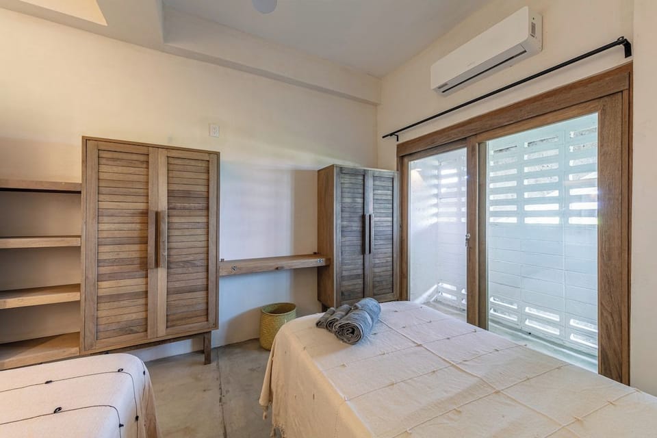 Second bedroom with two single beds and air conditioning.