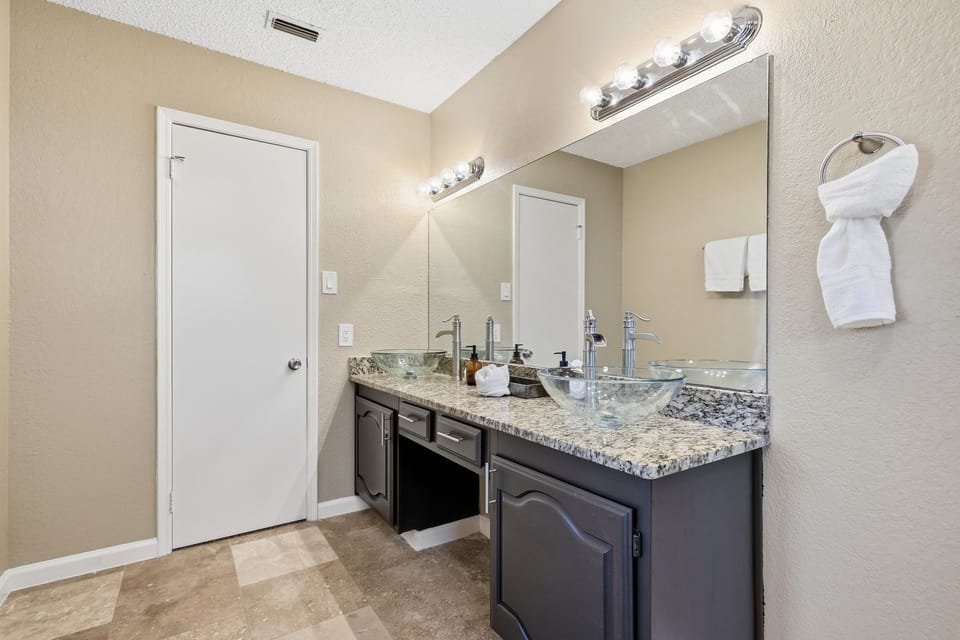 Spacious bathroom vanity featuring dual glass vessel sinks and granite counter.