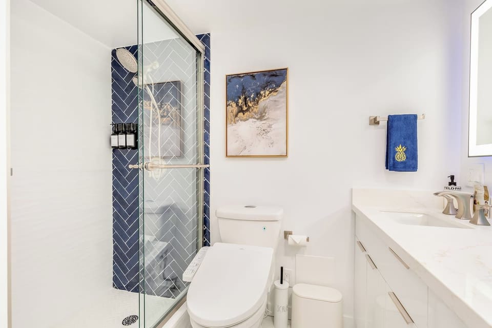 A full bathroom with backlit mirror and massage shower heads to help you get ready for a night out in Waikiki.