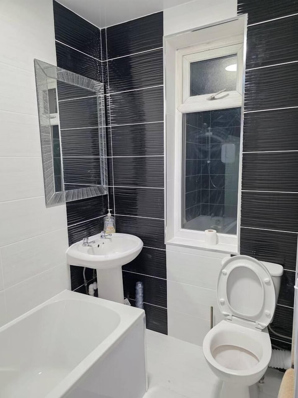 Bright modern bathroom with tub, sleek tilework, and natural light