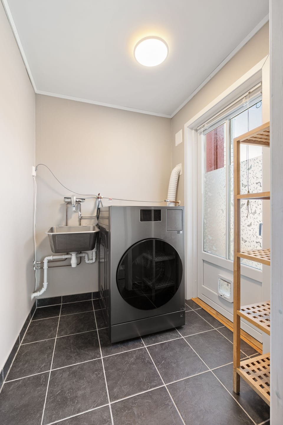 Bright laundry room with modern washer, utility sink, and handy storage