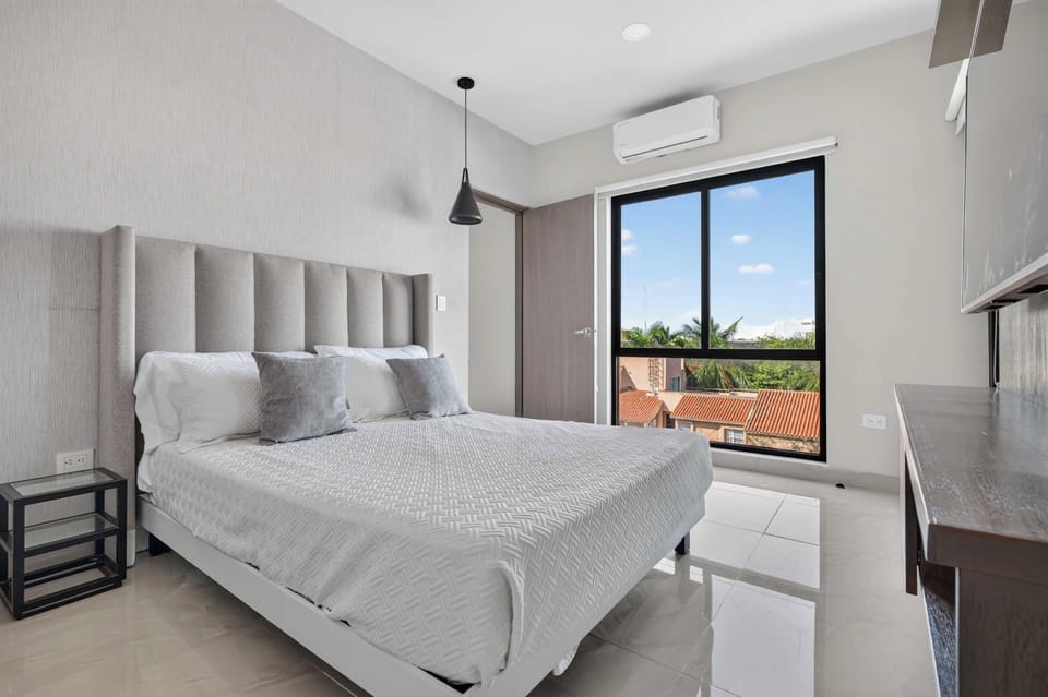 Bright bedroom with queen bed and window overlooking treetops