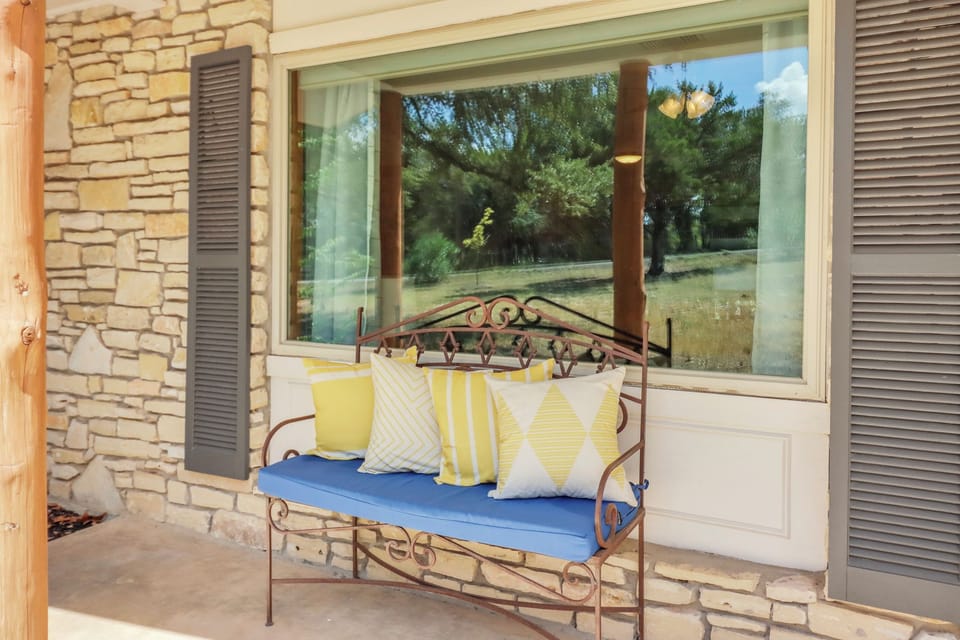 Your inviting covered patio with a cozy bench and cheerful yellow pillows���perfect for your morning coffee while gazing at the peaceful natural landscape just beyond.