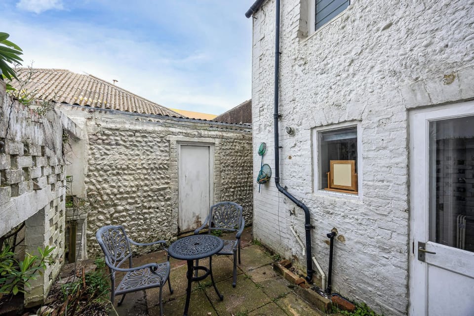 Small private patio, quiet and enclosed with a simple seating area. A peaceful spot for fresh air, morning coffee or a relaxed drink after a day by the sea.