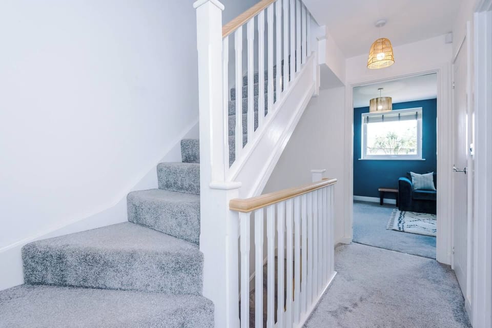 Bright carpeted staircase and airy hallway with stylish modern touches