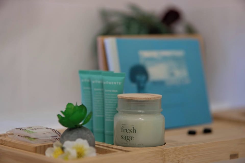Bamboo tray with fresh sage candle, skincare products, and delicate floral accents — a thoughtful welcome touch that adds a spa-like calm to the bathroom from the moment you arrive.