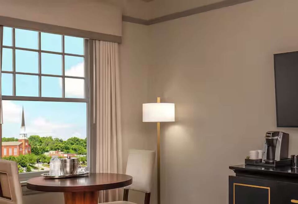 Seating area by window with table, chairs, and coffee setup