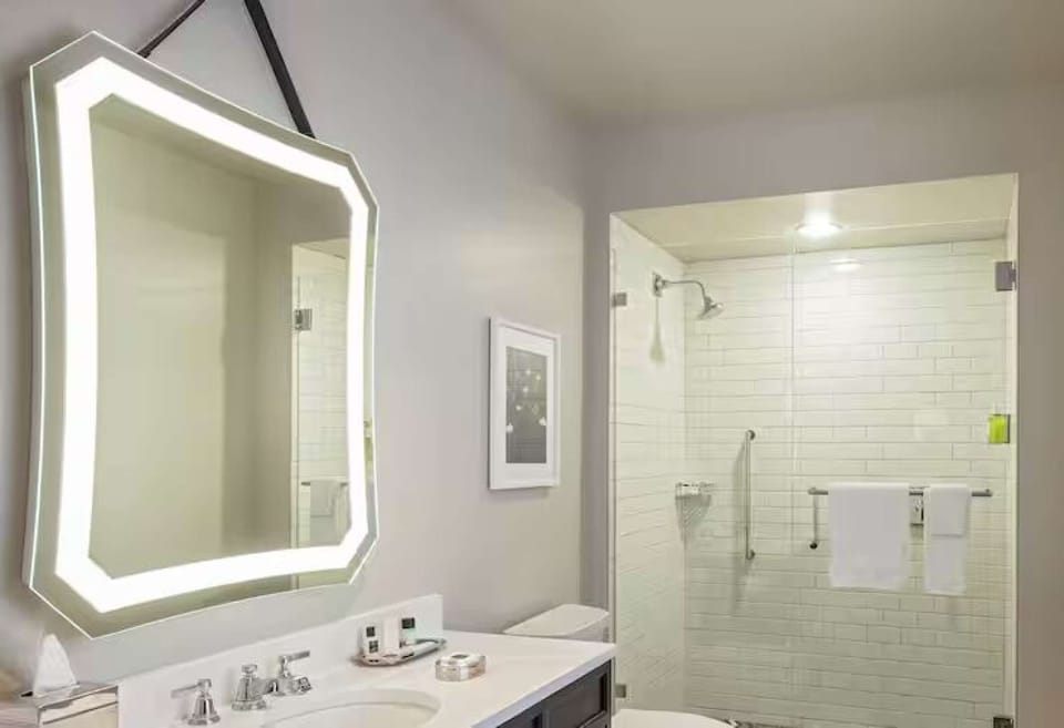 Bathroom with lit mirror, sink, and glass shower enclosure