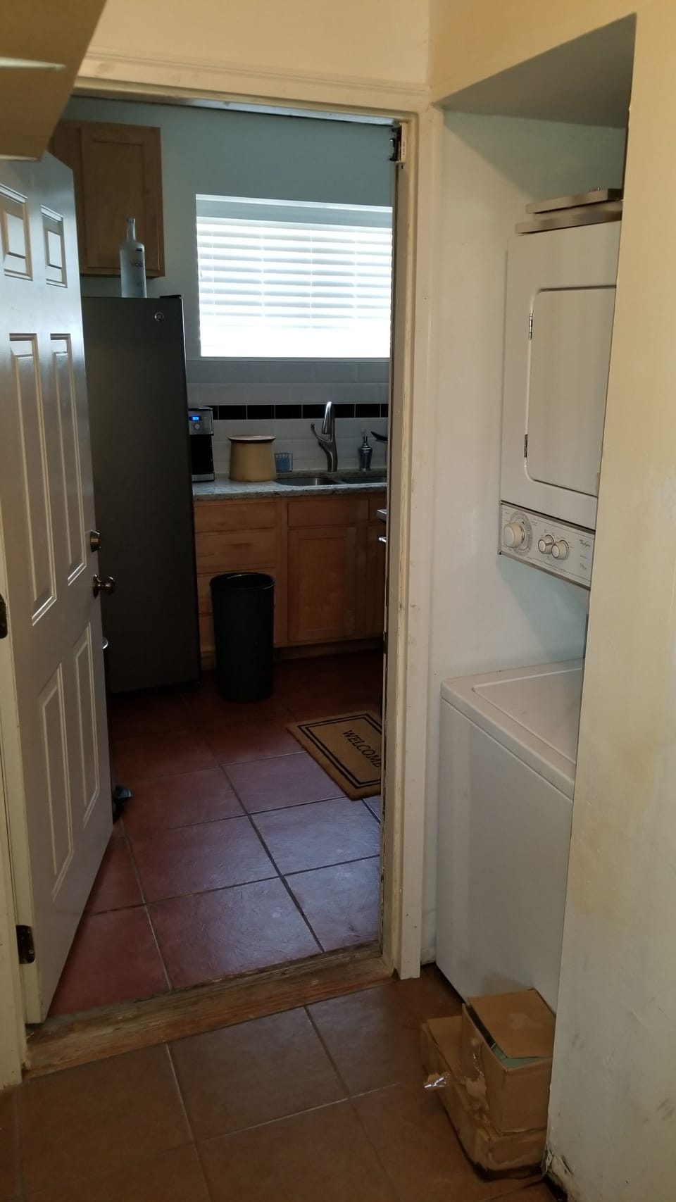 Hallway to kitchen with stacked washer-dryer