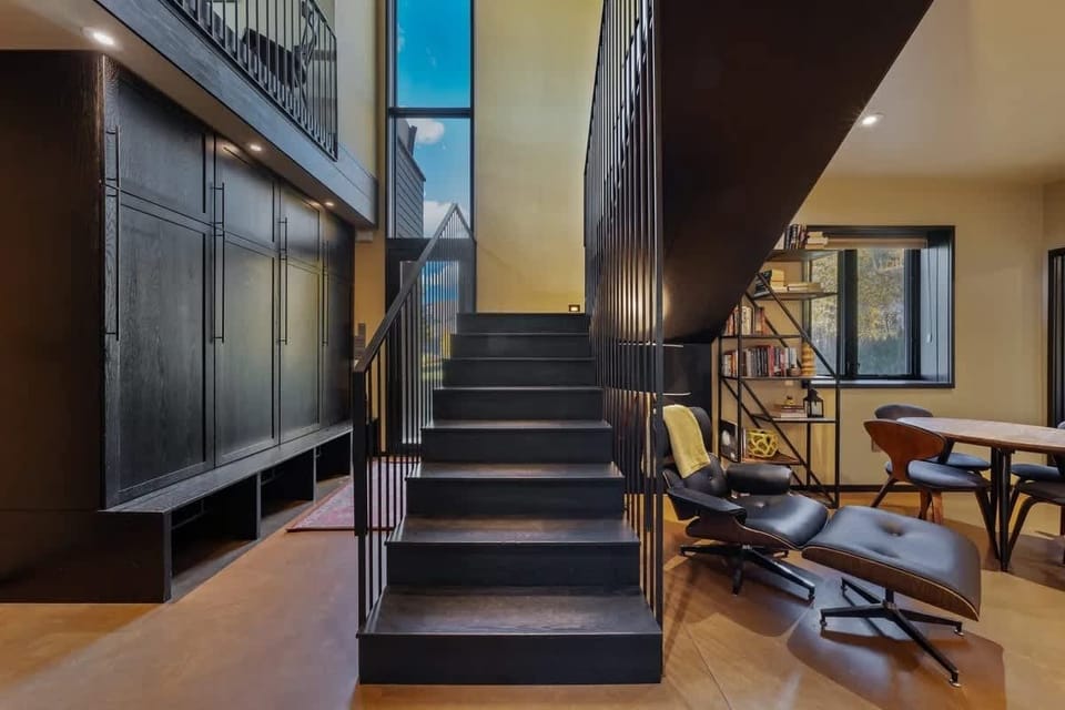 Sleek dark stairs lead to a cozy reading corner with a classic lounge chair. Curl up with a book and enjoy a quiet escape from the busy day.