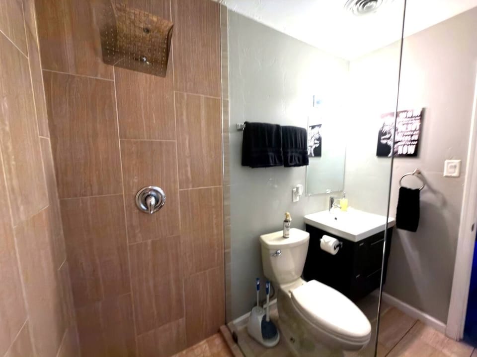 Freshen up in the sleek walk-in shower with a rainfall showerhead, paired with a modern vanity and glass enclosure that give this primary bathroom a spa-like, upscale feel guests love.