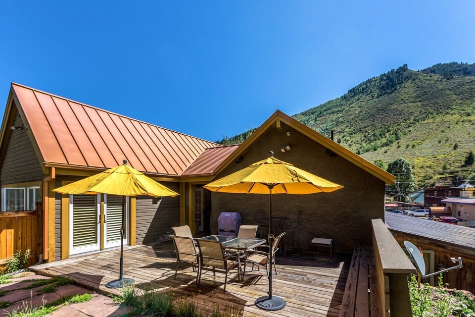 Outdoor wood deck with furniture, umbrellas, and gas grill.